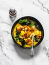 Vegetarian pumpkin, potatoes, beans and kale stew - delicious autumn lunch on a light background, top view