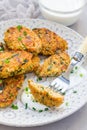 Vegetarian quinoa, carrot, coriander and green onion fritters with yogurt on plate, vertical