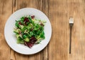 Vegetarian salad of fresh vegetables on a white plate on a wooden background Royalty Free Stock Photo
