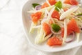 Vegetarian salad from raw fennel slices, grapefruit and red onions on a white plate, close-up shot with copy space, selected focus