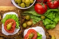 Vegetarian sandwiches with healthy rye bread, cheese cream, tomatoes, green olives and lettuce on table, top view. Healthy food Royalty Free Stock Photo