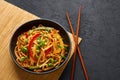 Vegetarian Schezwan Noodles or Vegetable Hakka Noodles or Chow Mein in black bowl at dark background. Indo-chinese cuisine hot