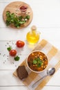 Vegetarian soup with beans and olives and tomatoes in a ceramic cup, olive oil on a yellow linen napkin on a white wooden Royalty Free Stock Photo