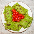 Vegetarian spinach green pancakes and small red tomatoes Royalty Free Stock Photo