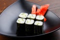 Set sushi rolls with ginger on a black plate on a dark wooden background. Royalty Free Stock Photo