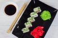 Vegetarian sushi rolls on a black square plate with wasabi, soy sauce and ginger. White wooden background Royalty Free Stock Photo