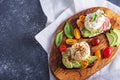 Vegetarian toast with poached eggs, cottage cheese, avocado, spinach, cherry tomatoes on wooden Board on gray background Royalty Free Stock Photo