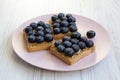 Vegetarian toasts with peanut butter, blueberries and chia seeds on a pink plate over white wooden surface, top view. Healthy eati Royalty Free Stock Photo