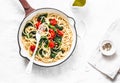 Vegetarian whole grain spaghetti pasta with cherry tomatoes and spinach sauce in a cast iron pan on a white background, top view. Royalty Free Stock Photo