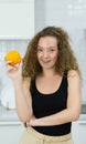 vegetarian woman smile, happy, show orange in hand, looking at camera in kitchen. beautiful caucasian woman cooking healthy diet