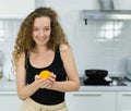 vegetarian woman smile, happy, show orange in hand, looking at camera in kitchen with copy space. beautiful caucasian woman