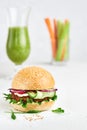 Veggie burger with celery smoothies, carrots and cerely on a white deck with copy space Royalty Free Stock Photo