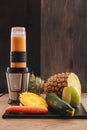 Veggie juicy made in a blender of pineapple, apple, cucumber and carrot in a dark wood background Royalty Free Stock Photo