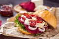 Vegitarian burger with beet slices, microgreen sprouts, tofu cheese, dried tomatoes and onion on kraft package paper on dark stone