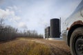 Vehicle parked in front of bitumen oil storage tanks on an oil lease