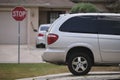 Vehicle parked in front of wide garage double door on paved driveway of typical contemporary american home Royalty Free Stock Photo