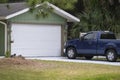 Vehicle parked in front of wide garage double door on paved driveway of typical contemporary american home Royalty Free Stock Photo