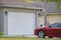 Vehicle parked in front of wide garage double door on paved driveway of typical contemporary american home