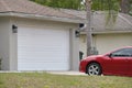 Vehicle parked in front of wide garage double door on paved driveway of typical contemporary american home