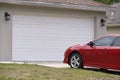 Vehicle parked in front of wide garage double door on paved driveway of typical contemporary american home