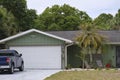 Vehicle parked in front of wide garage double door on paved driveway of typical contemporary american home Royalty Free Stock Photo