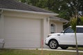 Vehicle parked in front of wide garage double door on paved driveway of typical contemporary american home Royalty Free Stock Photo