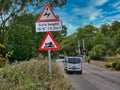 Vehicles pass signs warning of overhead electric cables and a risk of grounding as they approach a level crossing