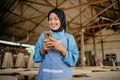 Veiled businesswoman enjoys using a cell phone at a woodcraft shop