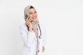 veiled doctor wearing white suit uniform listening on a call using a mobile phone happily with copyspace