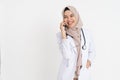 veiled female doctor in a white uniform smiling while making a phone call