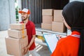 veiled female employee holding clipboard with male worker carrying boxes Royalty Free Stock Photo