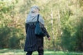 Veiled Muslim woman walking in public garden on back