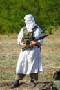 Veiled soldier in traditional islamic white clothes with the Kalashnikov gun