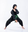 A veiled woman wears a pencak silat uniform with a green belt with a middle stance