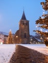 Velbert, Germany - January 17, 2021: Old Evangelical church covered with snow and Christmas trees with lights. Christmas mood