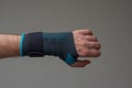 Velcro wrist stabilizer cast worn by Caucasian male hand. A blue split brace meant to aid Carpel Tunnel syndrome. Close up studio