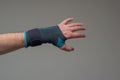 Velcro wrist stabilizer cast worn by Caucasian male hand. A blue split brace meant to aid Carpel Tunnel syndrome. Close up studio