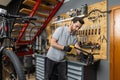 Velomechanic in professional attire servicing bicycle with specialized tools in workshop setting Royalty Free Stock Photo