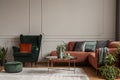 Velvet emerald green armchair with orange pillow next to corner sofa and coffee table Royalty Free Stock Photo