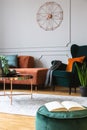 emerald green armchair with orange pillow next to corner sofa and coffee table