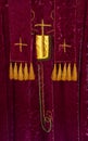 Velvet vestment & stole chasuble for Christian festival celebration. Closeup gold crosses & tassels hanging display.