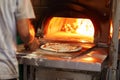 vendor baking pizza in mobile woodfired oven