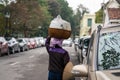 Vendor with basket of bread on head on Hanoi street, Vietnam. Two rows of cars parking on street. Concept of contrast between livi