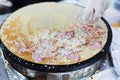 Vendor making crepe with ham outdoors