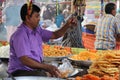 A vendor measuring traditional sweet food Jalebi/Jilapi at a shop of a local market