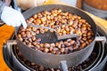 Vendor roasts chestnuts in a large machine, scooping them for customers Royalty Free Stock Photo