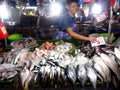 A vendor sells different kind of fishes at a wet market.