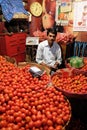 Vendor sits behind a large pile of tomatoes in New Market in Kolkata