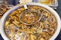 Vendor stirs a pot of simmering offal with a ladle, a street food delicacy