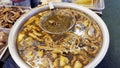 Vendor stirs a pot of simmering offal with a ladle